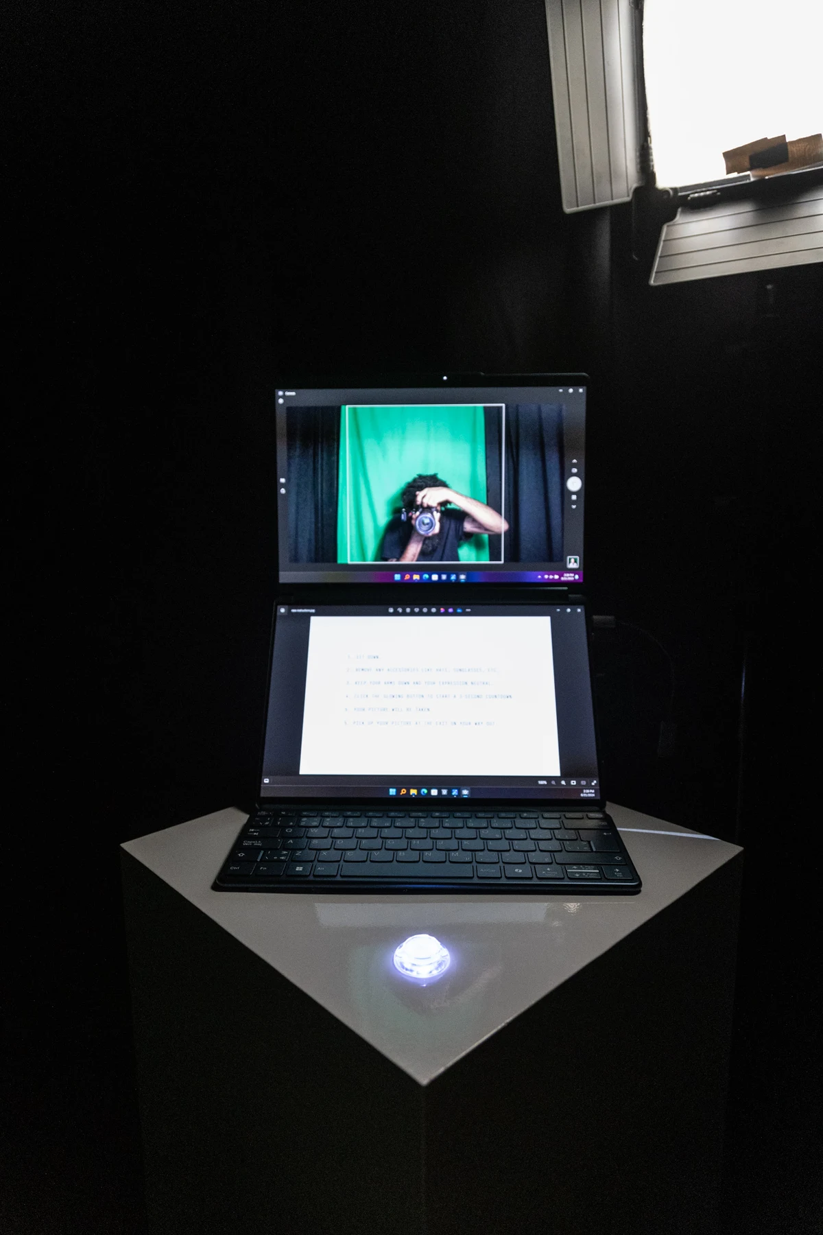 The same booth setup with a visitor now visible on its monitor, ready for a portrait.