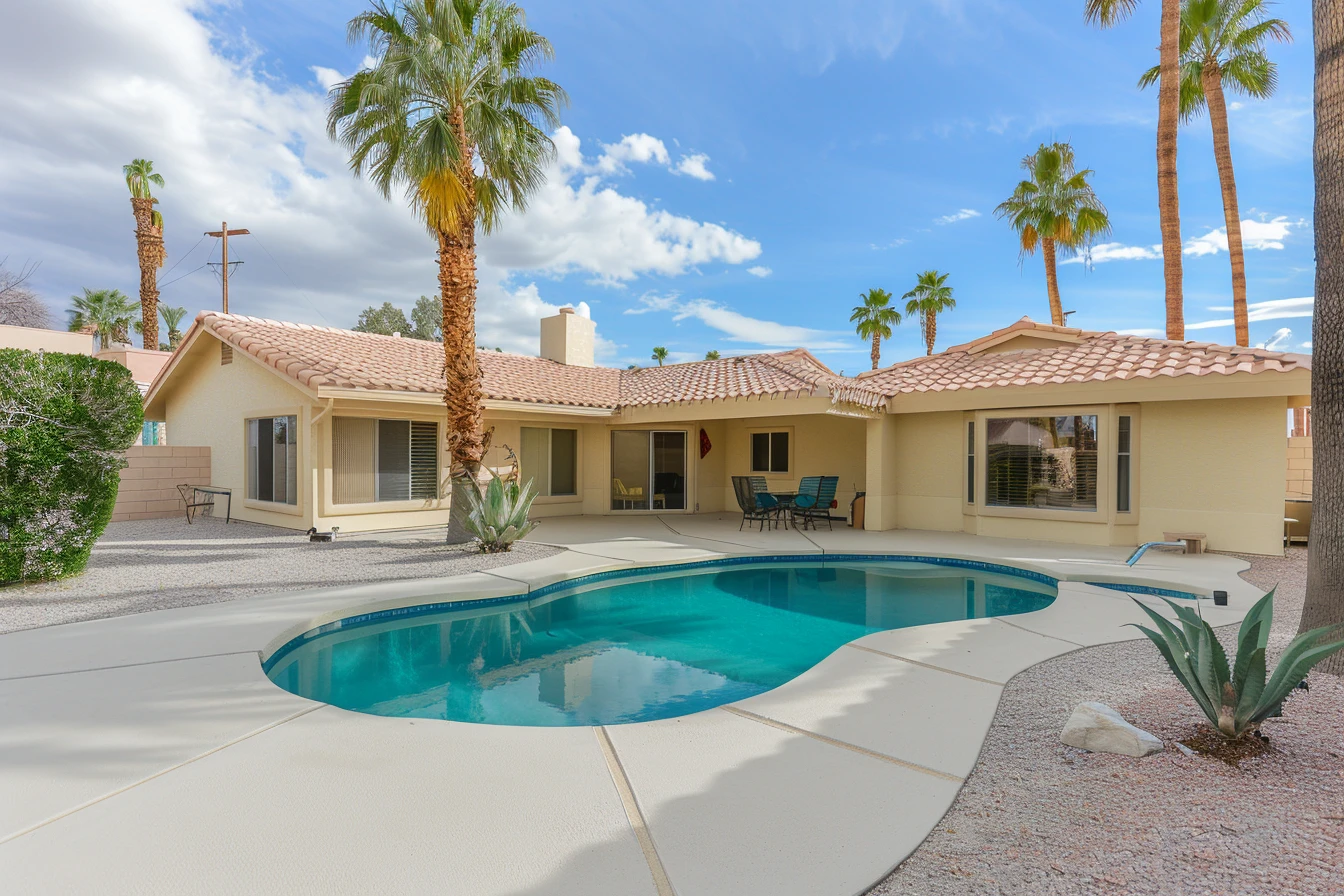 Supplied source image of a single-storey home with a tiled roof, palm trees and a curved swimming pool.